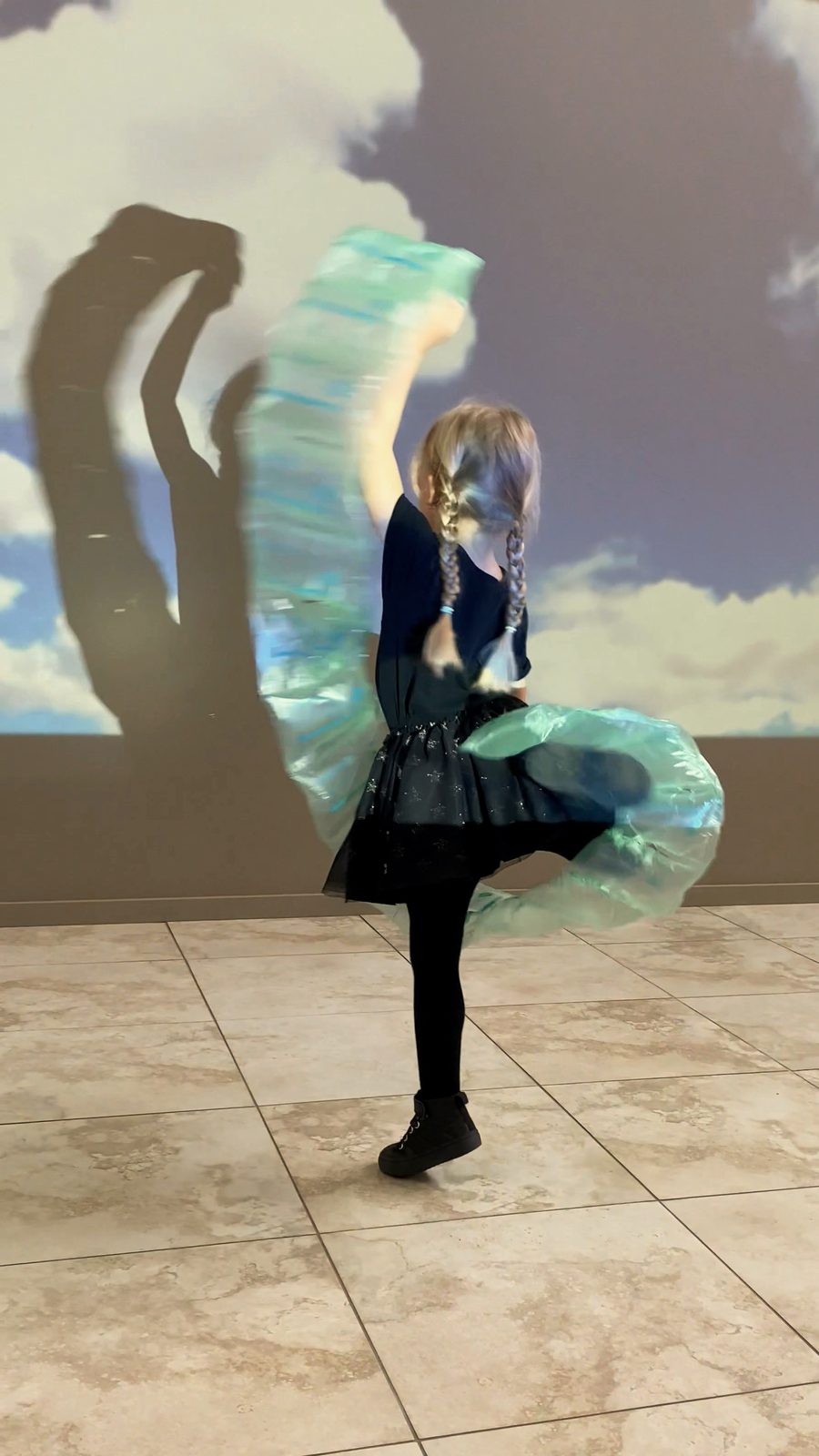 A child dancing with a silk scarf in front of a projected sky at a Bear Park centre